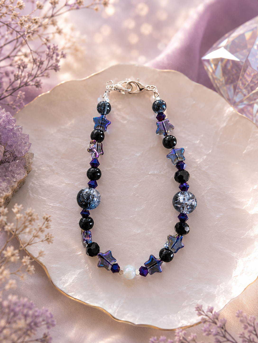 Midnight Star Beaded Bracelet with iridescent star charms and black onyx beads on a white shell dish